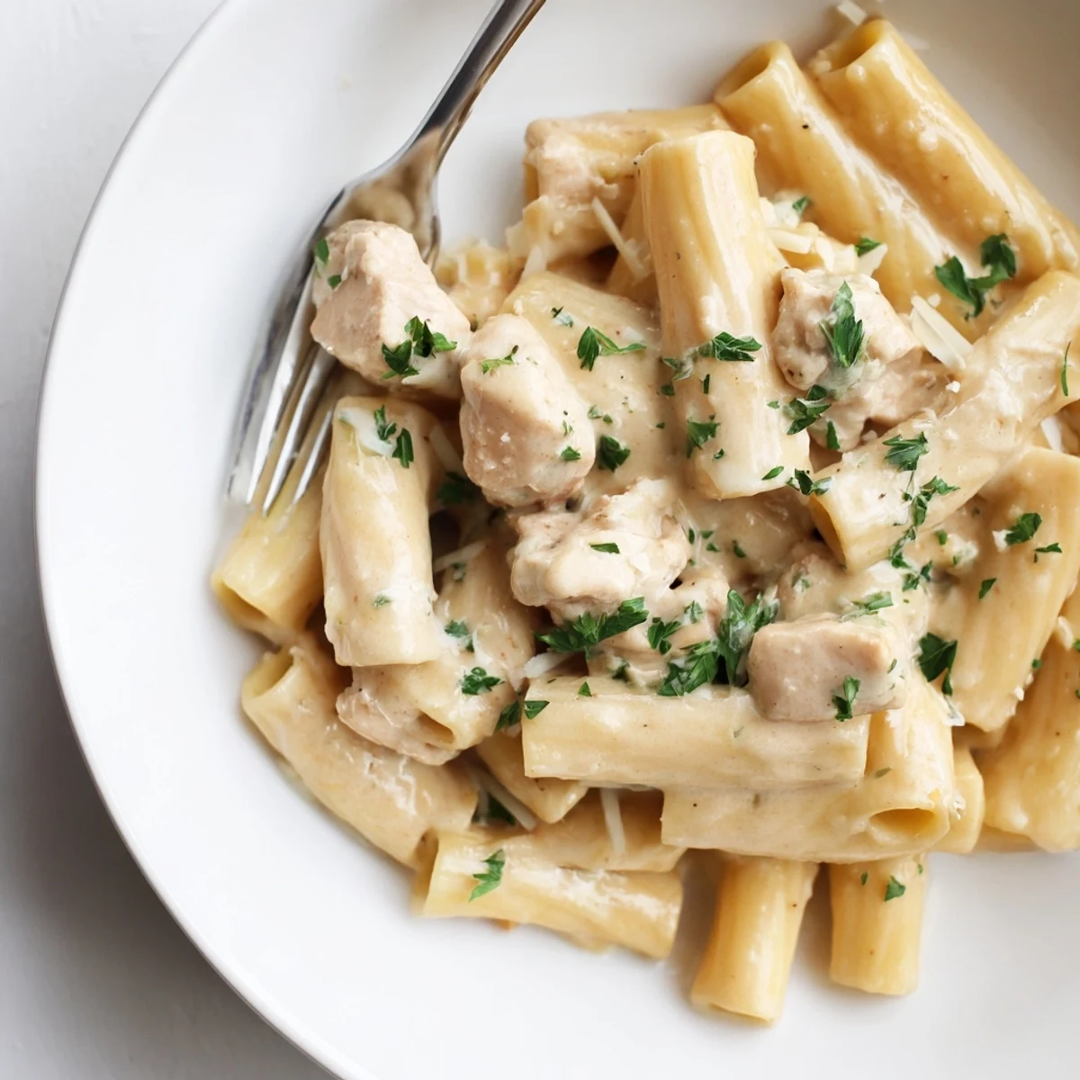 Creamy Garlic Parmesan Chicken Rigatoni in a rich sauce, garnished with parsley and cheese.  