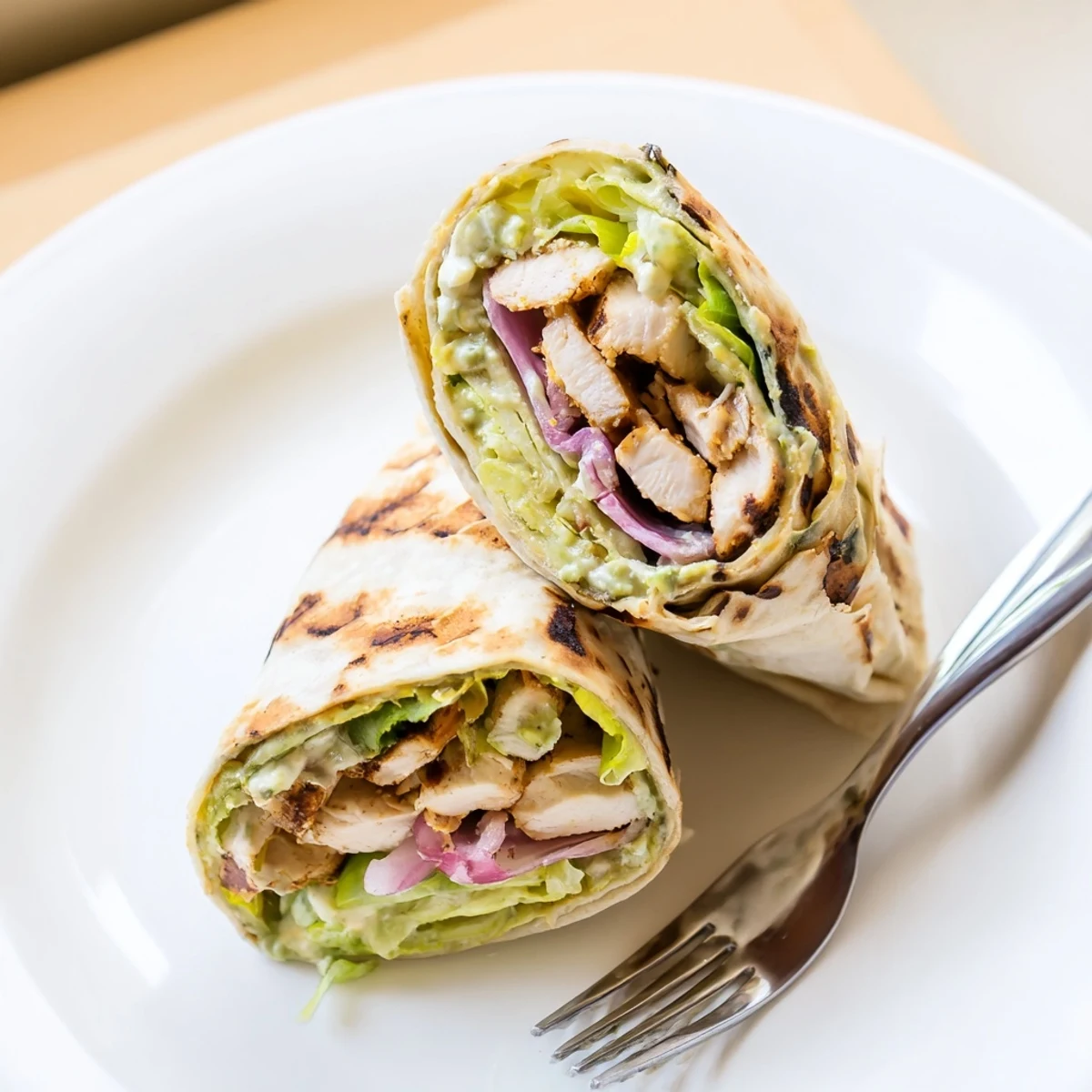 A vibrant Smoky Chipotle Chicken Wrap plated with crisp romaine, red onion, and a drizzle of tangy Greek yogurt sauce.  