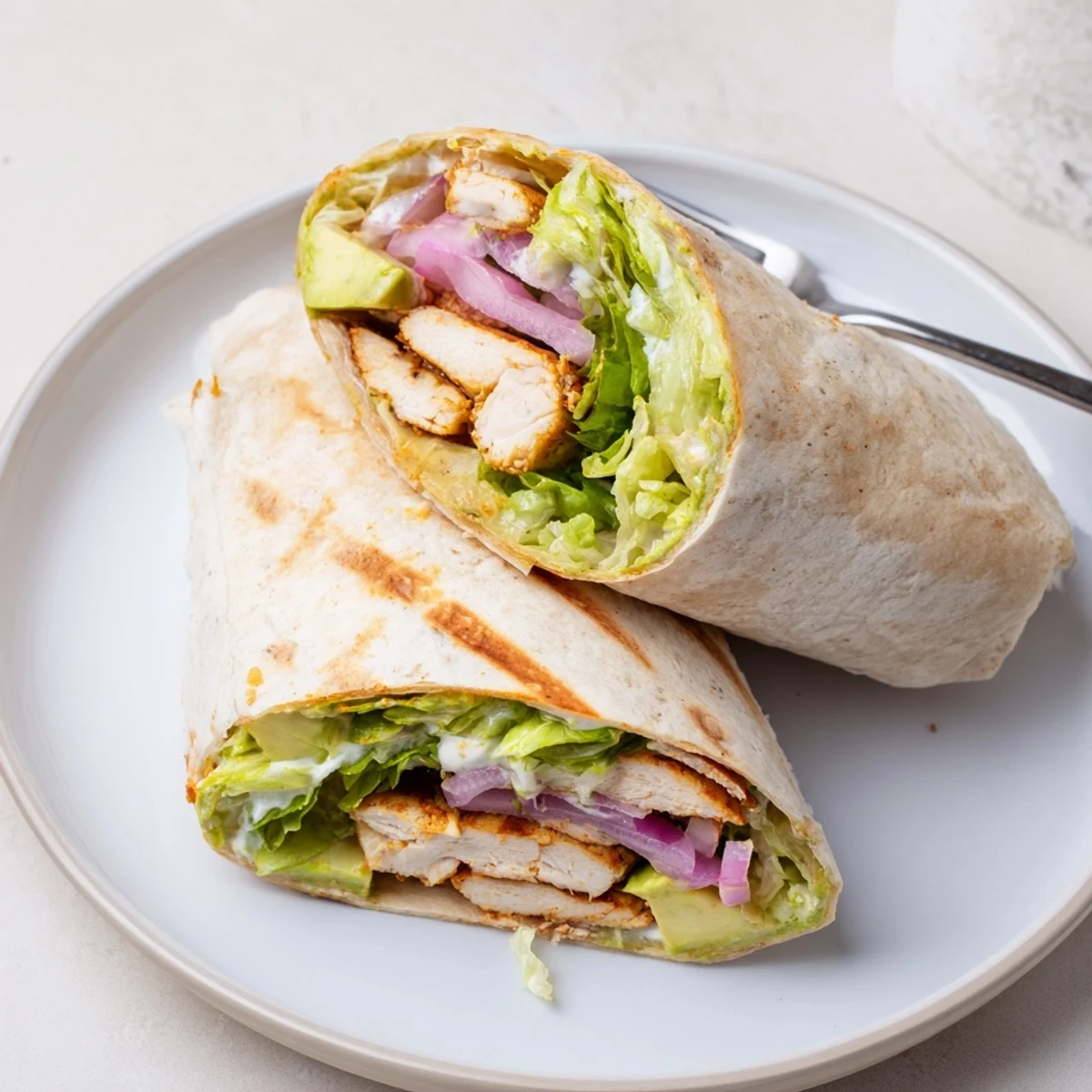 Freshly rolled Smoky Chipotle Chicken Wrap with smoky chicken, ripe avocado, and zesty cilantro-lime yogurt sauce, ready to eat.