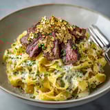 Perfectly seared Wagyu beef tops this creamy pasta, finished with glistening gold leaf, an exquisite dish.