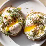 A beautiful plate of Çılbır Eggs Benedict shows vibrant yolks and fresh herbs, ready to enjoy.