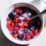 A close-up of Nature's Cereal Bowl highlights juicy berries swimming in chilled coconut water, a refreshing delight.