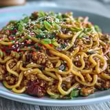 A skillet of Korean Turkey Fried Noodles shows sautéed bell peppers and ground turkey.