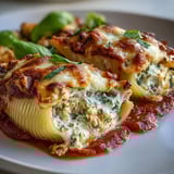 Golden-brown baked Pesto Lasagna Stuffed Shells, topped with melted mozzarella, fresh basil, and a rich marinara sauce in a dish.