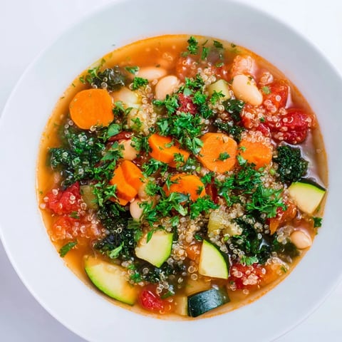Steaming hot Minestrone with Quinoa & Winter Greens garnished with fresh parsley, ready to enjoy.