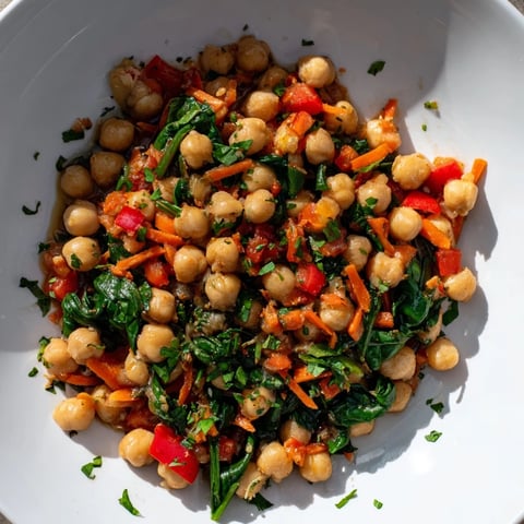 Steaming Vegetarian Chickpea & Spinach Skillet, vibrant with red pepper and aromatic spices, ready to serve.