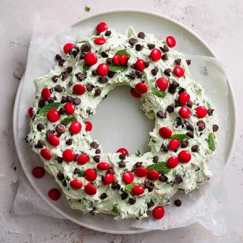 Festive Mint Chocolate Chip Dip Wreath, a creamy green dessert wreath topped with chocolate chips.