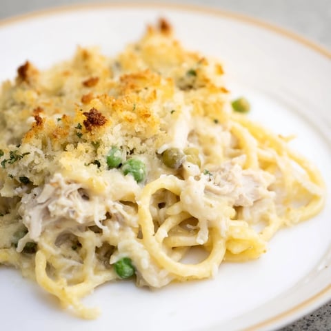 A bubbly, golden Turkey Tetrazzini bake with a crispy Parmesan topping, ready to serve with a fork.