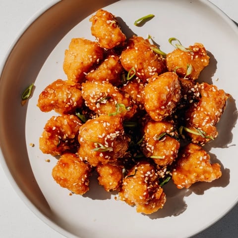 Golden-brown Honey-Sriracha Chicken Bites glistening with a spicy and sweet glaze, ready to enjoy.