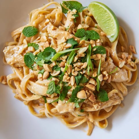 Steaming bowl of Thai Peanut Chicken Pasta, fragrant with fresh herbs and peanuts, ready to enjoy.