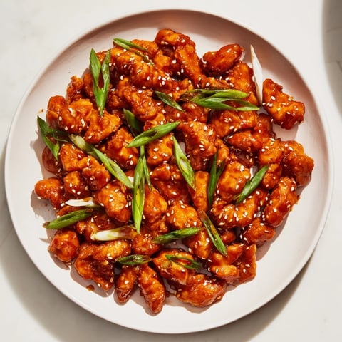 Juicy Sweet and Spicy Sriracha Honey Chicken, glazed and glistening, ready for a flavorful bite.