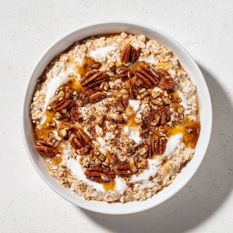 Steaming bowl of Pumpkin Spice Latte Oats, topped with whipped cream and chopped pecans.