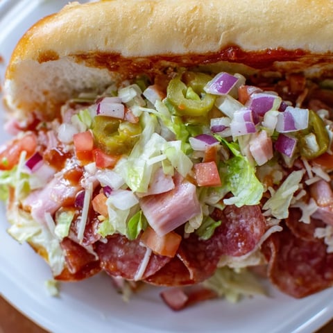 Chopped Italian Grinder sandwich overflowing with meats, cheese, and vegetables on a toasted roll.