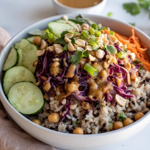 Freshly cooked brown rice topped with chickpeas, crunchy peanuts, and vibrant shredded veggies in a peanut dressing.
