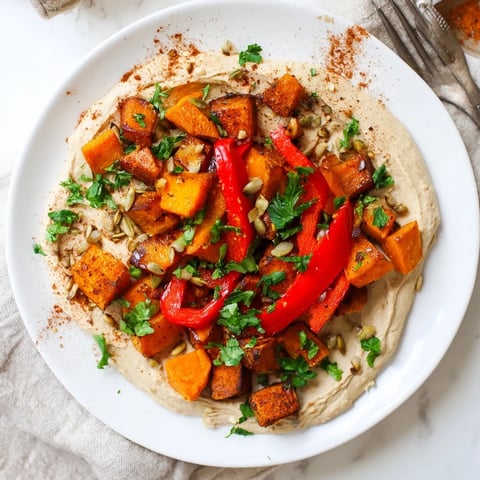 Golden roasted butternut squash and sweet potatoes are arranged over creamy butter bean hummus, with toasted seeds and fresh parsley for texture.