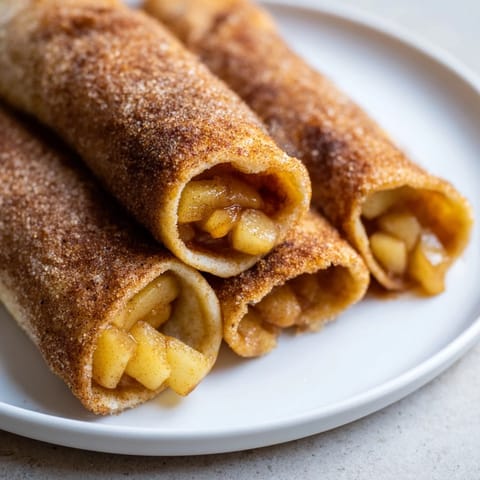 Close-up of baked Apple Pie Roll-Ups, showcasing the cinnamon-spiced apple filling inside the tortilla.