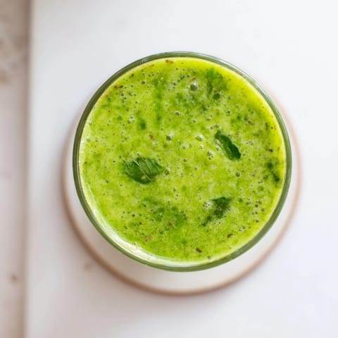 A refreshing glass of Green Detox Smoothie garnished with mint leaves, ready for a revitalizing morning start.