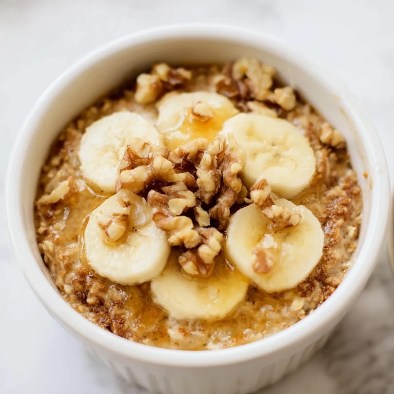 Steaming-hot, individual Baked Oats Ramekins with fresh bananas, perfect for a cozy morning breakfast.