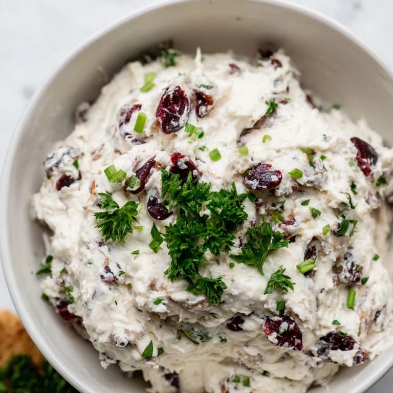 This festive Lightened Holiday Cream Cheese Dip, garnished with herbs and nuts, is a lighter appetizer option.