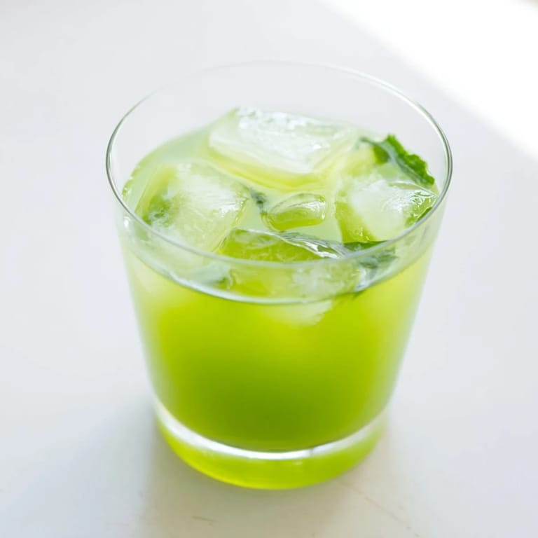 Overhead view of Celery Ginger Lemon Juice blending in a high-speed blender, showing ice cubes, chopped celery, ginger, and lemon slices ready to mix.