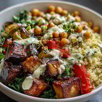 Golden Mediterranean Buddha Bowl Meal Prep features roasted eggplant, steamed kale, sweet peppers, and chickpeas over bulgur pilaf, drizzled with creamy tahini dressing and topped with crunchy pistachios.