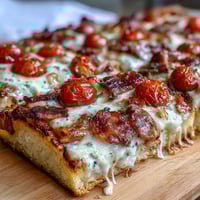 Golden flatbread pizza topped with roasted turkey, crispy bacon, juicy tomatoes, and creamy Mornay sauce, perfect for Derby Day parties.