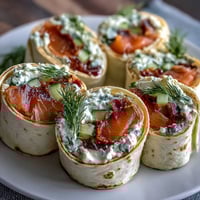Smoked salmon and cucumber cream cheese pinwheels with dill on a white platter